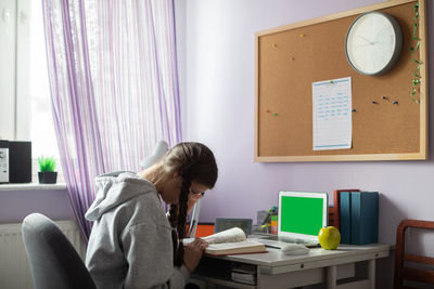 Green screen. a student with braids and glasses at home is reading a book.