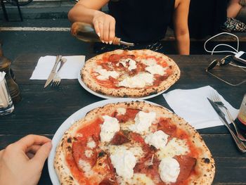 Midsection woman pouring sauce on pizza at outdoors restaurant