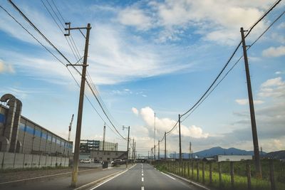 Electricity pylon by road against sky