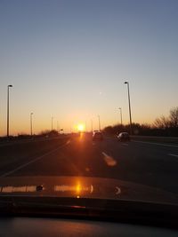 Cars on road against sky during sunset