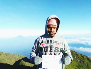 Portrait of young man standing on mountain against sky