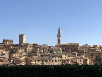 Buildings in city against clear blue sky