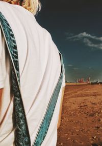 Rear view of woman standing on beach against sky