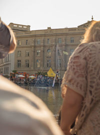 People on river by city against clear sky