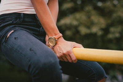 Midsection of woman holding hands sitting outdoors