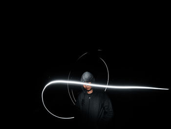 Man standing against illuminated light over black background