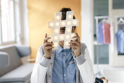 Young woman hiding behind hashtag sign in studio