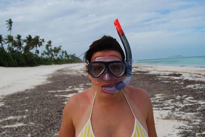 Portrait of young woman standing with snorkel at beach