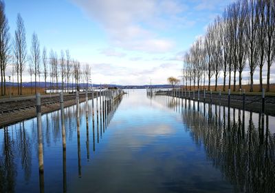 Wooden posts in lake against sky