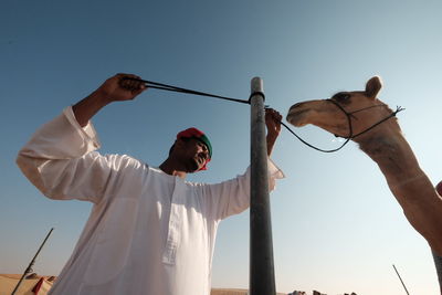 Low angle view of man holding umbrella against clear sky