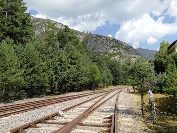 Railroad tracks by mountain against sky