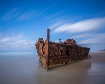 Abandoned boat on sea against sky