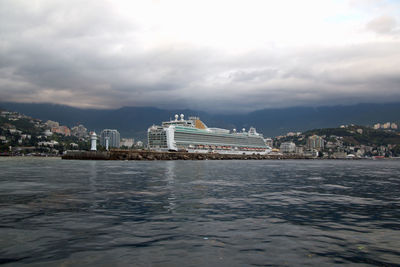 City at waterfront against cloudy sky