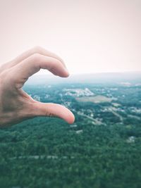 Close-up of hand on landscape against clear sky