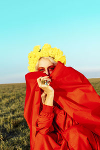 Portrait of woman holding red umbrella against clear sky