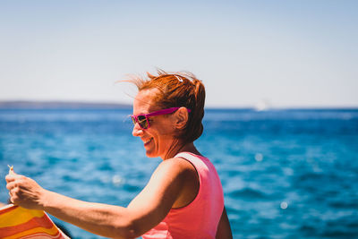 Smiling woman in sunglasses against sea