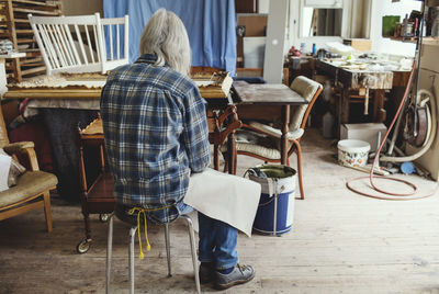 Rear view of woman sitting on table at home