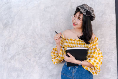 Portrait of a smiling young woman holding camera