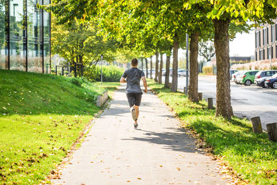 Rear view of man walking on footpath in city