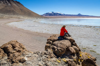 Woman on rock by mountain against sky