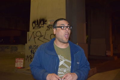 Surprised man with mouth open looking away by bridge at night