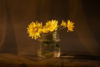 Still life with a bouquet of yellow flowers in a glass can 