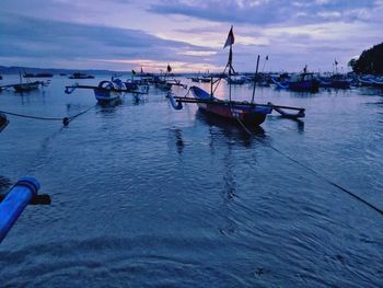 Boats moored on sea against sky during sunset