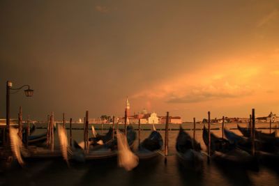 Blurred motion of boats moored at harbor against sky during sunset