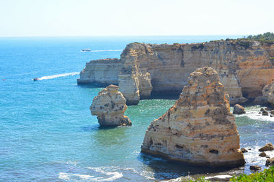 Rock formations in sea against clear sky