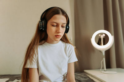 Portert a generation z teenager girl in headphones, sadly looks down.