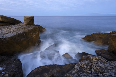 Scenic view of rocks in sea against sky