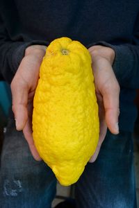 Close-up of hand holding yellow fruit