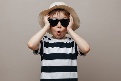 Portrait of boy wearing sunglasses standing against gray background