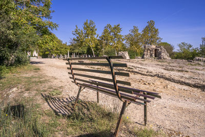 Empty benches on field against sky