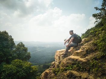 Man on rock by mountains against sky