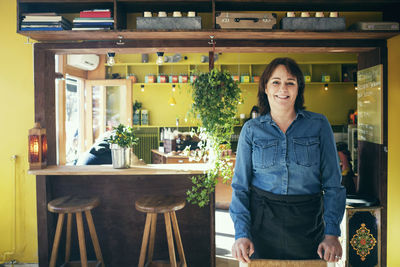 Portrait of happy owner standing in coffee shop