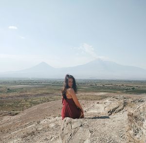 Woman with umbrella on land against sky