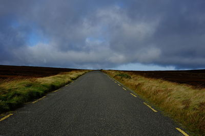 Road amidst field against sky
