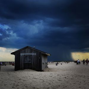 People on beach against sky during sunset