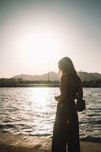 Woman standing by river against sky