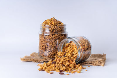 Close-up of bread in glass jar on table against white background