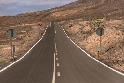 Empty road amidst landscape against sky