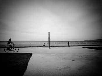 Man riding bicycle on beach against sky