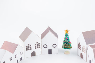 Close-up of christmas tree and model homes against white background