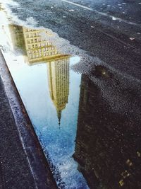 Reflection of building in puddle on street