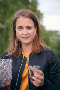 Portrait of smiling young woman holding drink during party on terrace