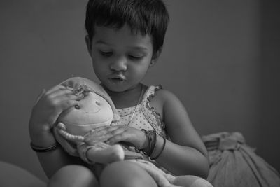 Black and white portrait of a cute baby girl playing with a soft toy