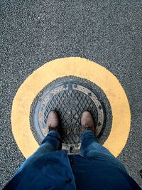 Low section of man standing on manhole