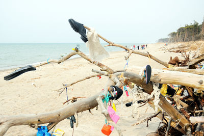 View of driftwood on beach with shoes and plastic waste