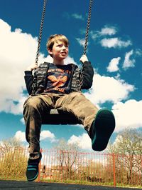 Low angle view of boy swinging in park